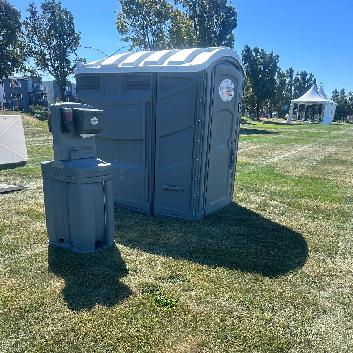 Wide-format portable restroom and hand wash station on a grass field, available in Rodeo