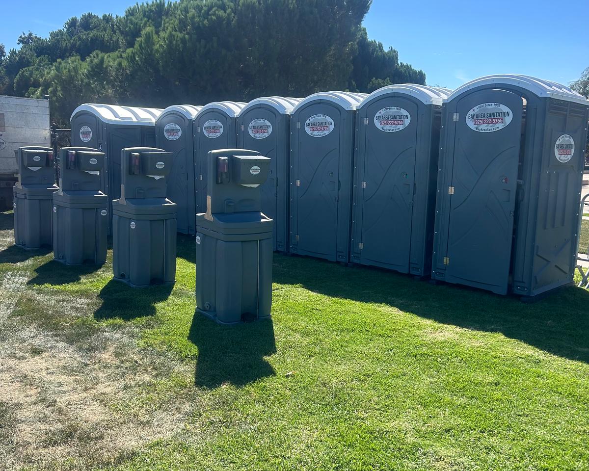 Eight portable toilets and four hand wash stations on a lawn, Discovery Bay rentals