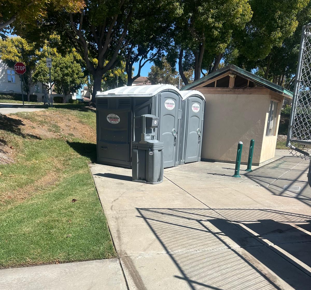 Two portable toilets and a hand wash station by a park building, Marin City rentals