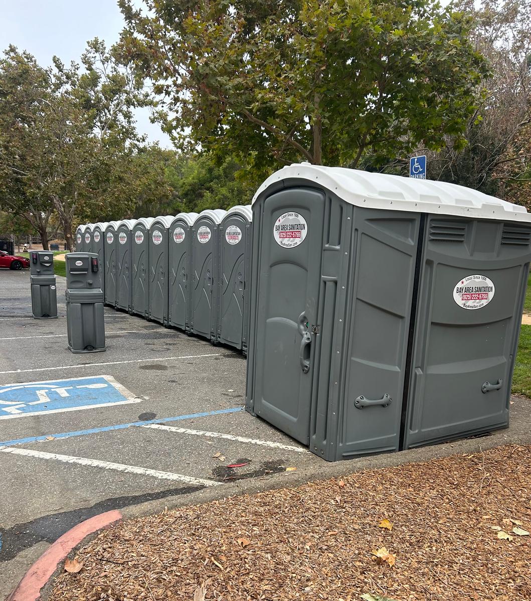 Row of portable toilets and hand wash stations in a parking lot, available in Vacaville