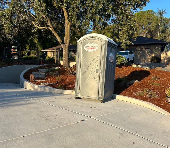 Porta potty on a freshly poured concrete driveway, available for construction projects in Blackhawk