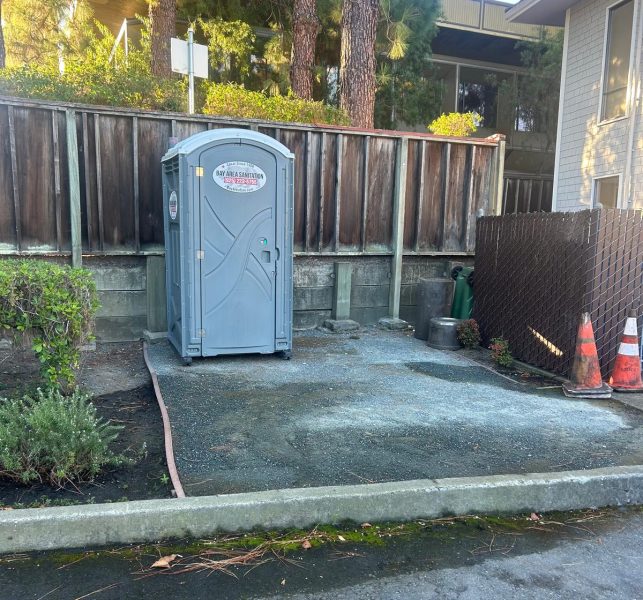 Porta potty on a gravel pad by a wood fence, available for Cordelia job sites