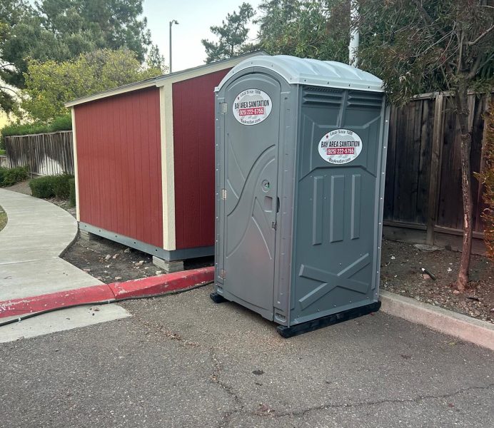Porta potty next to a red storage shed, available for Morgan Hill job sites