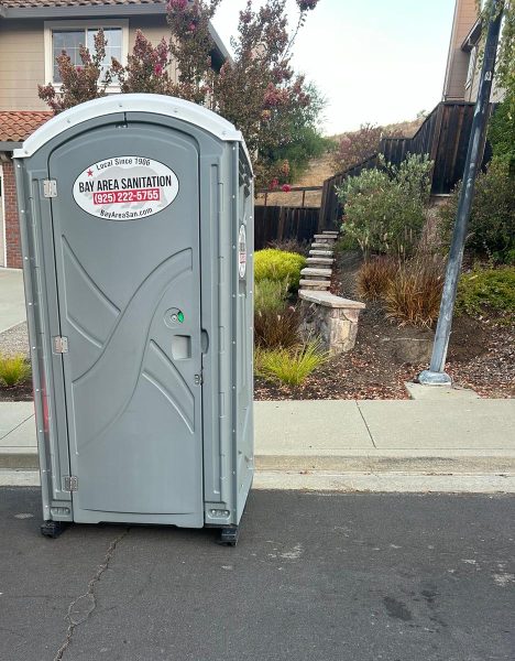 Standard porta potty at the curb of a residential street, available for rent in Rodeo